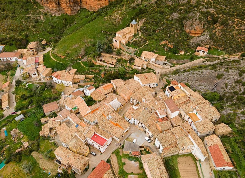 Aerial view of a village with traditional buildings nestled against a green hill with steep cliffs, aerial view, Las Peñas de Riglos, As Penyas de Riglos, rock formation Mallos de Riglos, Huesca, Aragon, Spain