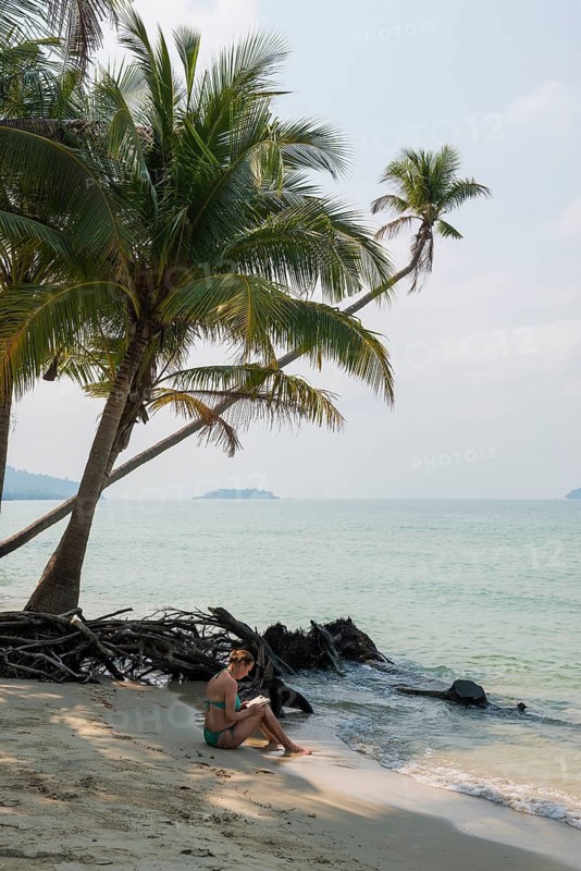 Picturesque beach with coconut palms and reading woman, Ko Chang, Koh Chang, Mu Ko Chang National Park, Trat, Thailand