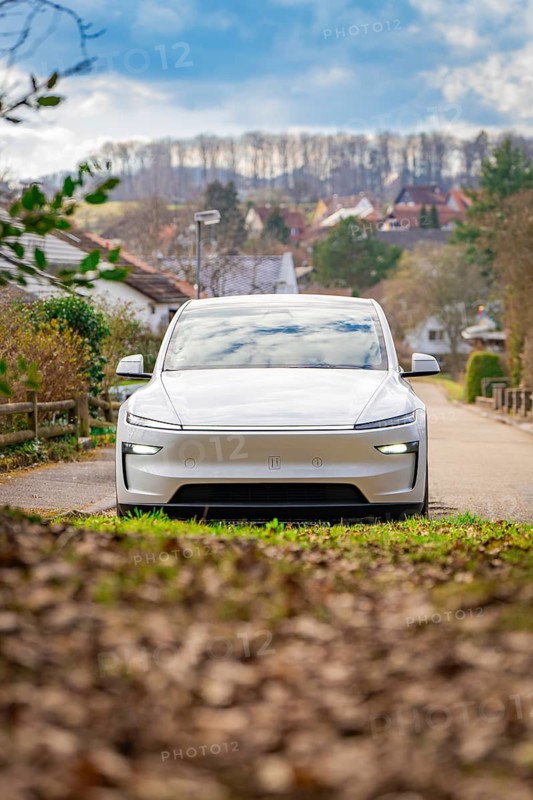 Electric car on quiet country road, surrounded by nature and clouds in autumn landscape, Tesla, New Model Y Juniper, Germany