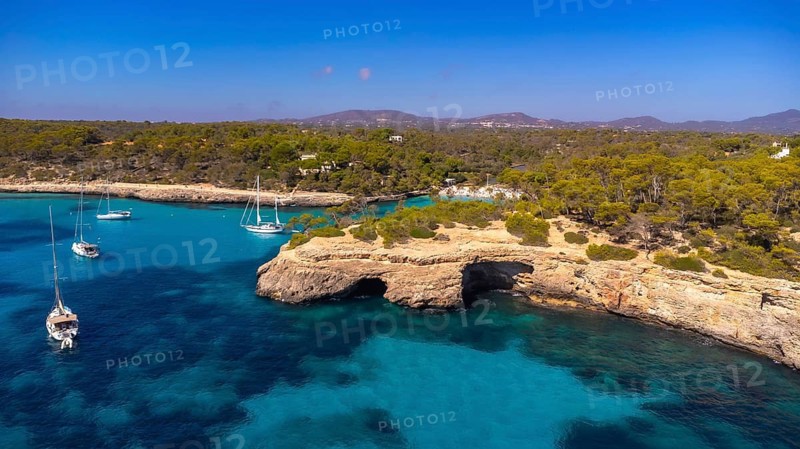 Breathtaking aerial view capturing sailboats gliding through the crystal clear turquoise waters of cala s'amarador and cala mondrago in mallorca, spain