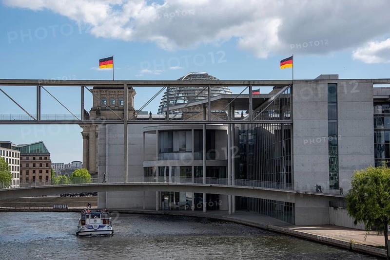 Modern building in Berlin's government district with Reichstag building, German flags and the Spree, Berlin, Germany