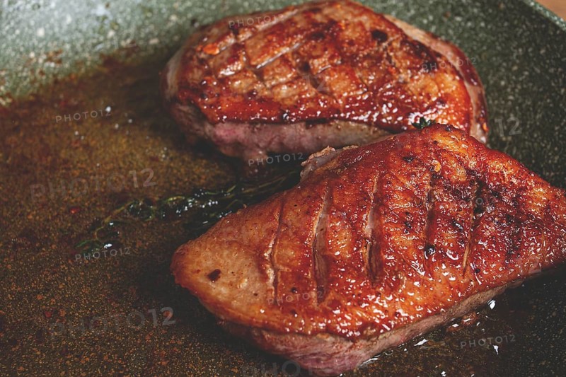 Cooking duck breast, in a frying pan, fried, with spices and herbs, close-up, no people