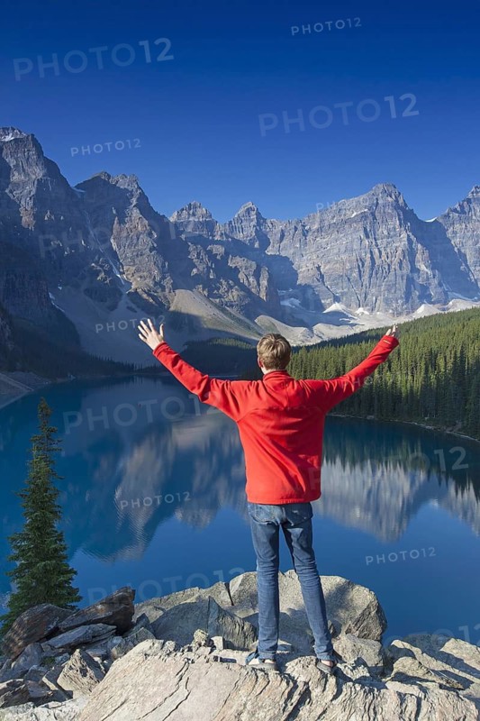 Tourist with open arms on look-out point looking over Moraine Lake in the Valley of the Ten Peaks, Banff National Park, Alberta, Canada | MR:yes Arndt Kobbe