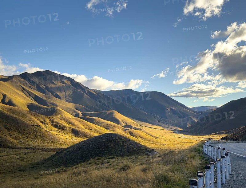 Serene beauty of autumn on Mount Cook, New Zealand, where golden hues blanket the landscape. The majestic mountains are stunning under a clear blue sky