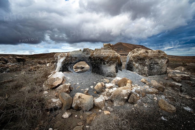 Eroded rock formations in volcanic landscape with dramatic cloudy skies, Ciudad Estratificada or Los Roferos, Antigua Rofera de Teseguite, Lanzarote, Canary Islands, Spain