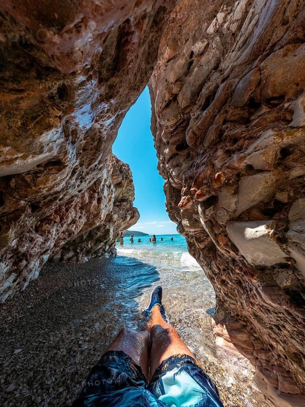 Sitting on the paradise beach of Kroreza or Krorez in a cave on the Albanian riviera in Sarande, Albania