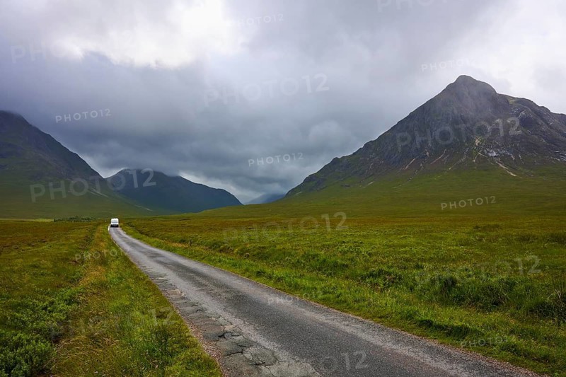 A lonely road leads through a vast landscape of dramatic mountain silhouettes and clouds, Glen Etive, Scotland, United Kingdom, Great Britain