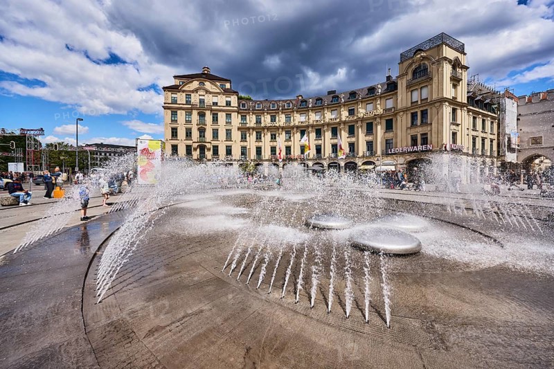 Fountain, general architecture, historic buildings, stachus roundel, neo-baroque style, architect Gabriel von Seidl, pedestrian zone, square, pedestrians as a secondary motif, blue sky, white and dark gray cumulus clouds, Stachus, Karlsplatz, Munich, state capital, district-free city, Bavaria, Germany