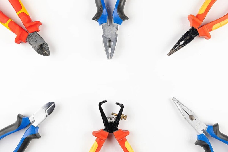Several colorful pliers arranged in a circle on a white background