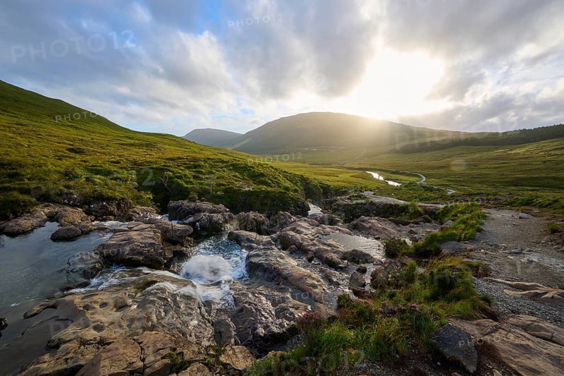 River flows through green hills in sunset light under a cloudy sky, Fairy Pools, Grula, Isle of Skye, Scotland, United Kingdom, Great Britain