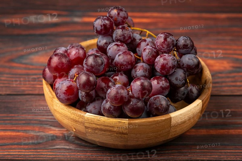 Fresh grapes in a wooden bowl on a dark wooden background