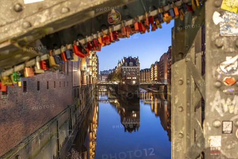 Water castle in Hamburg's Speicherstadt at blue hour with love locks in the foreground and reflection in the water, Hamburg, Germany