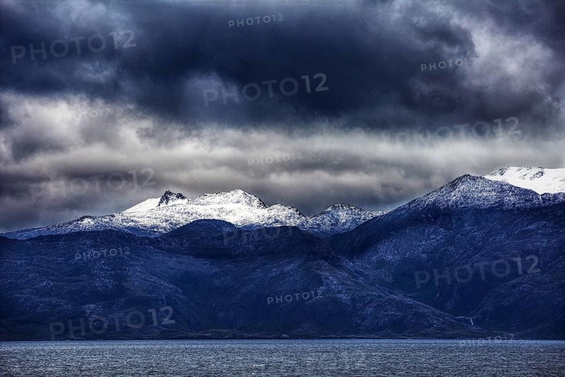 Snowy mountain peaks under dark, dramatic ocean clouds, Chile, South America