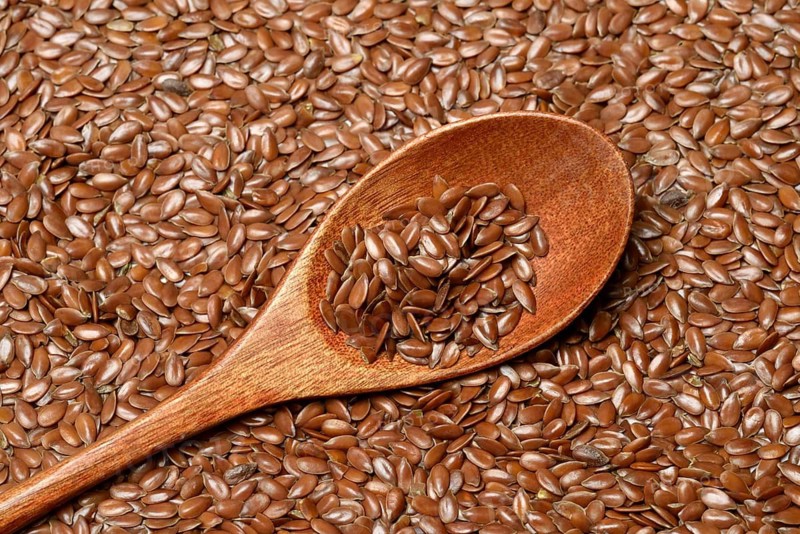 Linseed with wooden spoon, seeds of the common flax (Linum usitatissimum)