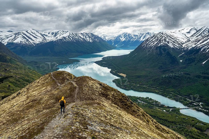 Climbers on a hiking trail on Slaughter Ridge, views of snowy mountains in spring and turquoise Lake Kenai Lake, Cooper Landing, Kenai Peninsula, Alaska, USA