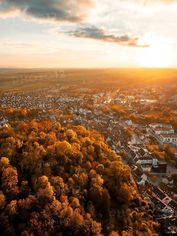 Cityscape in autumn light from above, surrounded by colourful trees at sunset, Herrenberg, Germany