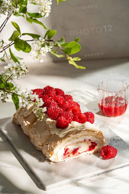 A visually delightful raspberry meringue roulade, featuring a light and airy cream filling, topped with fresh raspberries. Perfect for a sweet, indulgent treat