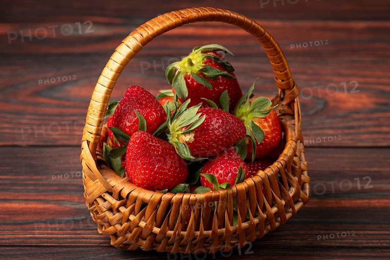Fresh strawberries in a basket on dark wood