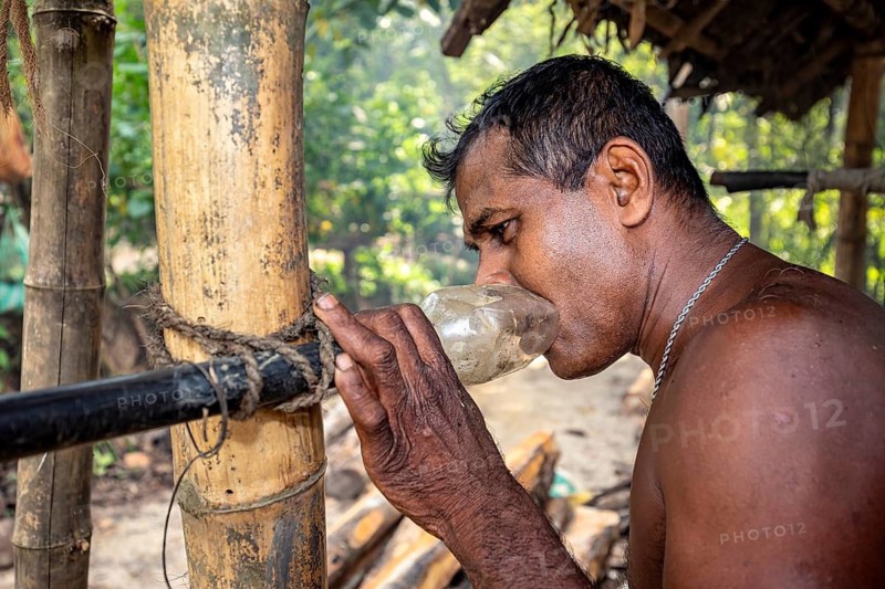 Man drinks concentrated from a makeshift container next to a bamboo cane, the sapphire and gemstone mines at Ratnapura in Sri Lanka