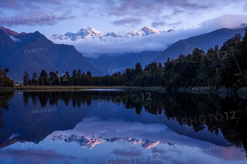 Lake Matheson (Te Ara Kairaumati) after sunset, reflection of the mountain peaks of Mount Cook and Mount Tasman, Southern Alps. Fox Glacier Area, Westland Tai Poutini National Park, West Coast, South Island, New Zealand