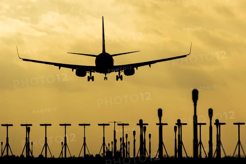 Boeing 737 commercial passenger airliner jet aircraft of Ryanair airways in flight on approach to land over runway lights at sunset at London Stansted airport, Essex, England, United Kingdom