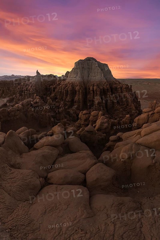 The mesmerizing sandstone formations in Goblin Valley State Park, Utah, are bathed in the warm hues of a stunning sunset, highlighting the park's unique geological beauty