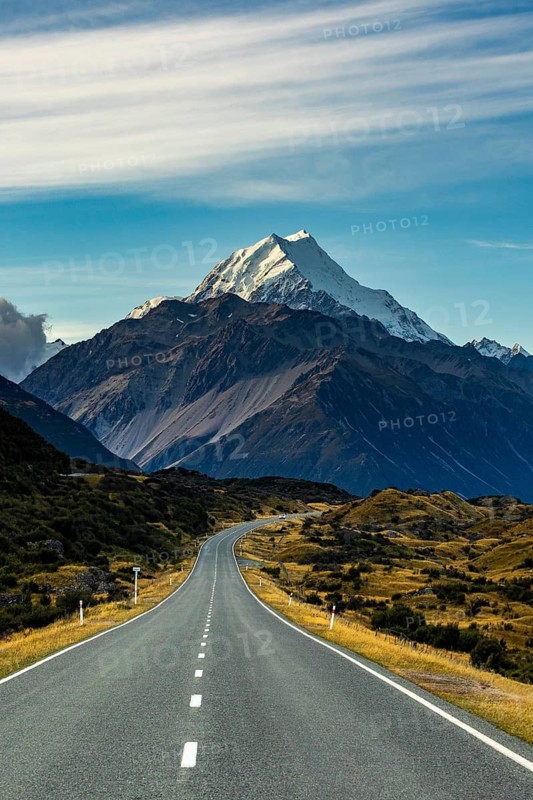Stunning autumn view of Mount Cook, New Zealand, showcasing a serene landscape with a winding road leading towards the majestic snow capped peak under a vibrant sky