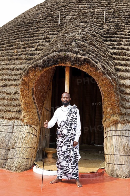 Rwandan man, 25 years old, wearing traditional dress at the entrance to the Royal Palace replica in the shape of a beehive, Nyanza, Rwanda