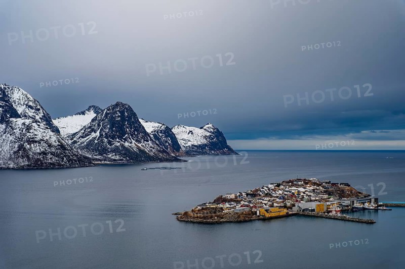 Husøy island in the fjord, snow-capped mountains behind it, Senja island, Troms, Norway
