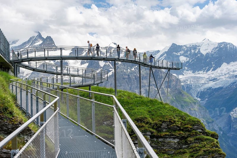 Tourists on the First Cliff Walk, metal trail on a rocky outcrop, Grindelwald First, in front of impressive mountain landscape with Schreckhorn summit and Upper Grindelwald glacier, tourist attraction, Bernese Alps, Bernese Oberland, Switzerland