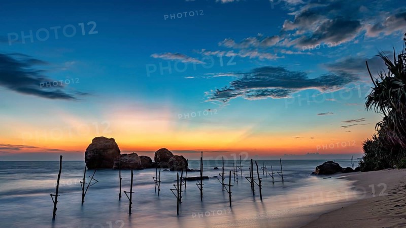 Blue twilight over the sea with wooden posts and quiet atmosphere, The stilt fishermen's beach near Koggala in Sri Lanka