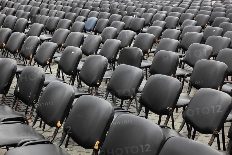 Chairs covered with gray plastic stand in rows in a function room, empty, vacant, seating