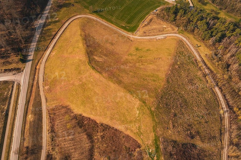 Aerial view of a hill with barren and vegetated areas, surrounded by roads, old deposit in front of PV Bau, Lindenrain, Calw, Germany