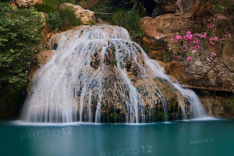 A focused waterfall falls over mossy rocks into a clear turquoise basin, waterfalls, ponds, Polylimnio, Peloponnese, Greece