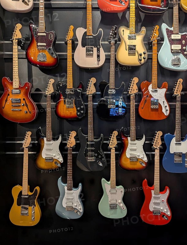 A colorful assortment of electric guitars is displayed on a wall, showcasing a variety of styles and finishes. Perfect for music lovers and guitar enthusiasts