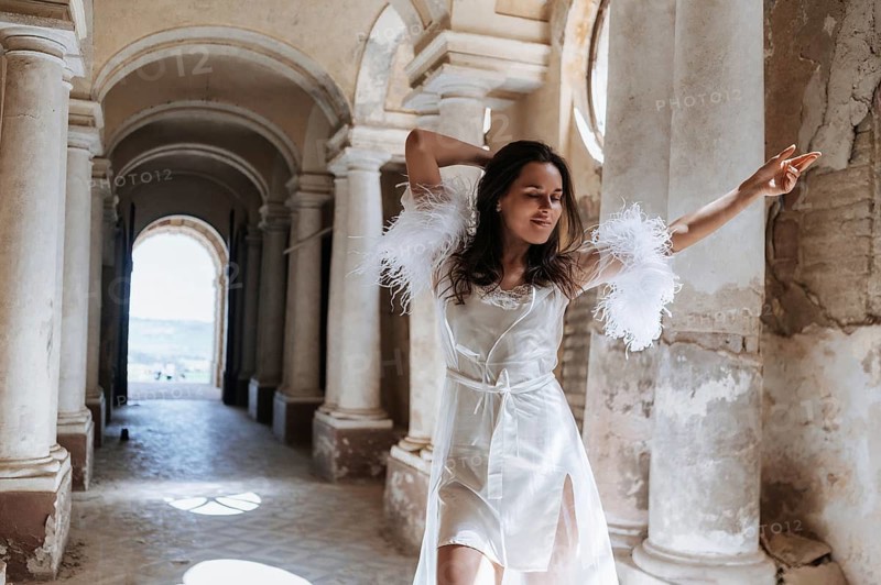 A bride wearing a delicate gown stands gracefully under the arches of an ancient villa in Treia, Macerata, capturing the timeless elegance of an Italian wedding