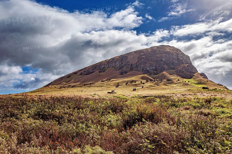 Green hill with cloudy sky and ancient rock formations, the landscape of Easter Island in the Pacific Ocean