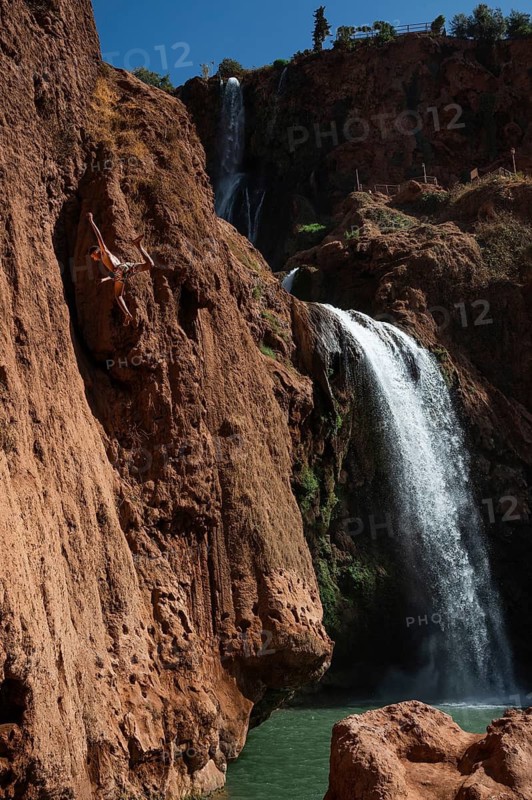 OUZOUD, MOROCCO - OCTOBER 5, 2024: A Moroccan young man jumps from the high rock into the water under a waterfall Ouzoud