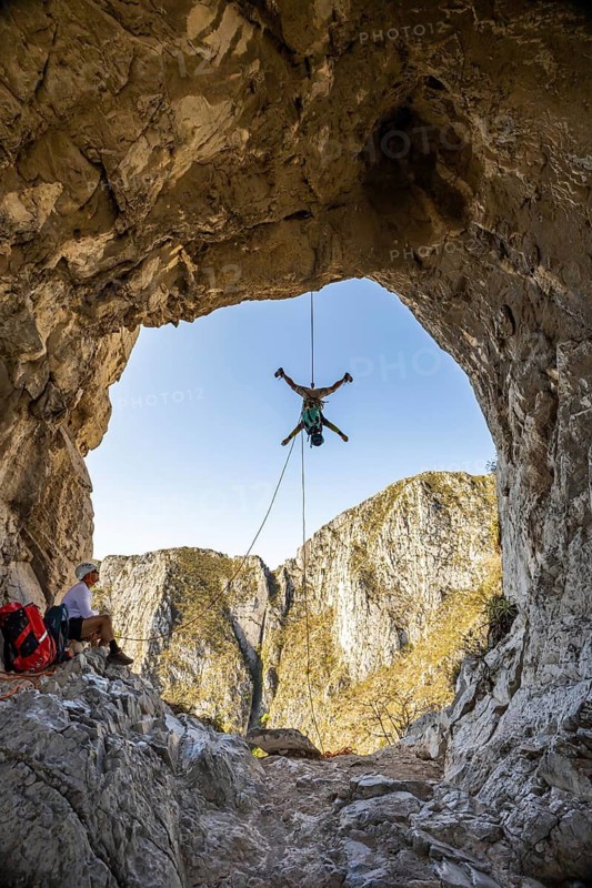 A man practices mountaineering and rappelling at Eagle's Nest, Monterrey, Mexico, demonstrating skill and adventure amid stunning rocky landscapes under clear skies