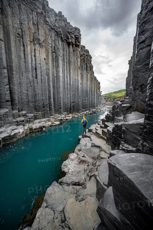 Tourist standing by the river in Stuðlagil Canyon, turquoise blue river between basalt columns, Egilsstadir, Iceland
