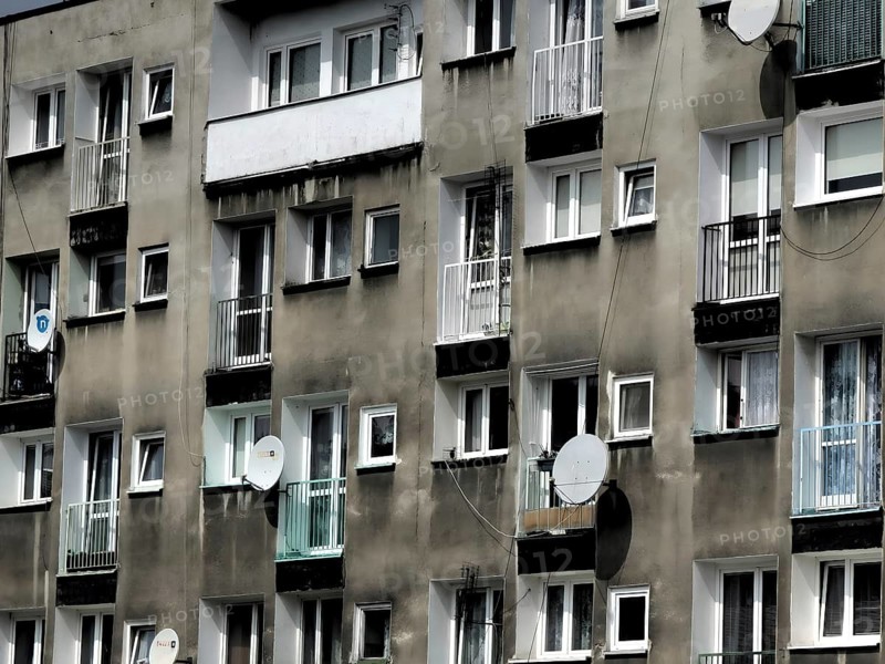 Façade, urban apartment block with numerous windows and satellite dishes on grey walls, Wroclaw, Poland