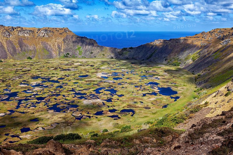 A large crater basin with small water pockets surrounded by a sublime volcanic landscape, the Ranu Kau volcano on Easter Island in the Pacific Ocean