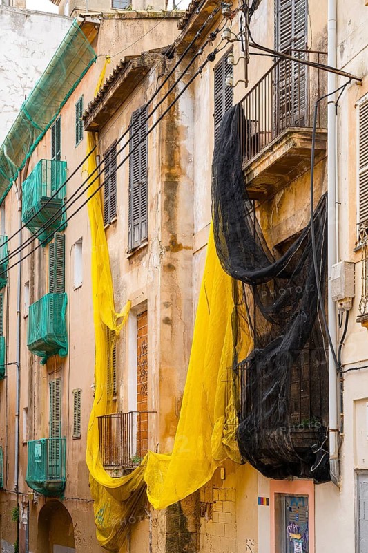 Yellow and black safety nets at the construction site of a house in Carrer de Sant Pere, Palma de Majorca, Spain