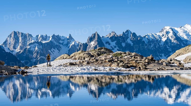Young man hiking along a mountain lake, mountain landscape in morning light, reflection in Lac Blanc, mountain peak, Aiguille Verte, Grandes Jorasses, Aiguille du Moine, Mont Blanc, Mont Blanc Massif, Chamonix-Mont-Blanc, Haute-Savoie, France