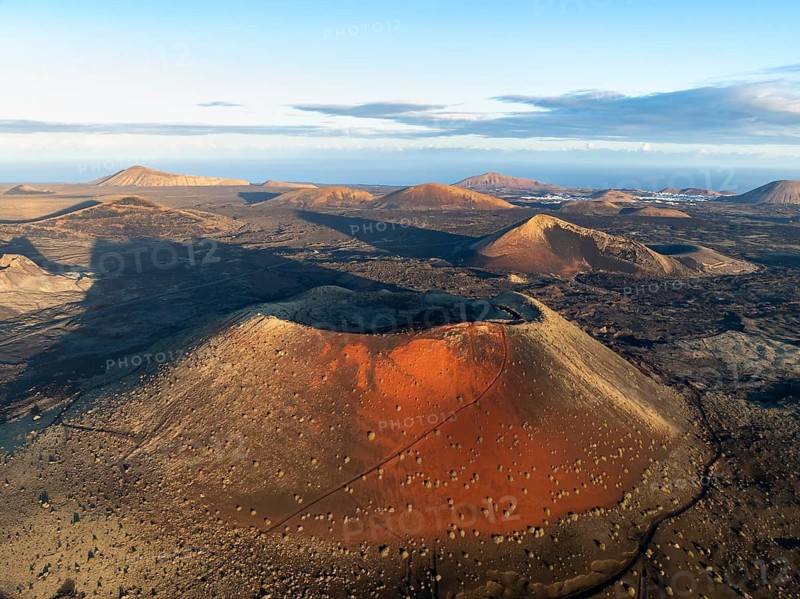 Picturesque volcanic landscape with volcanic craters and lava fields in morning light, Caldera Colorada volcano, Los Volcanes Natural Park, aerial view, Lanzarote, Canary Islands, Spain