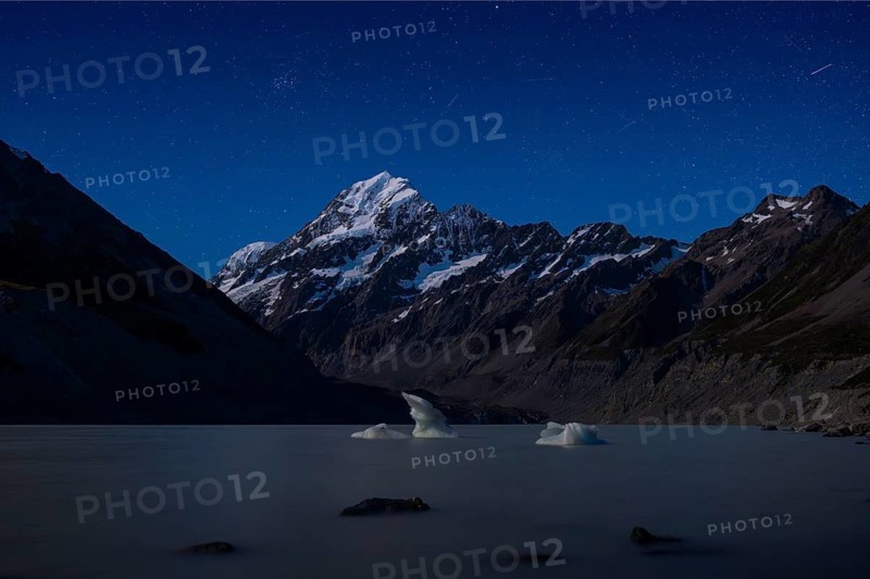 Mountainous landscape. Hooker Lake and Aoraki Mount Cook. At night, starry sky. Aoraki Mount Cook National Park, Canterbury, South Island, New Zealand