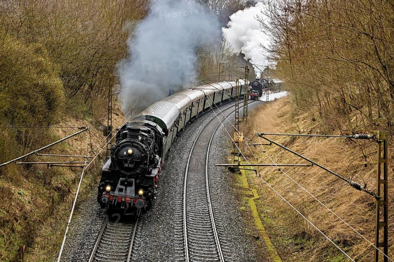 A steaming locomotive pulls a train through a wooded and winding route, historic steam locomotive journey between Bebra and Sontra