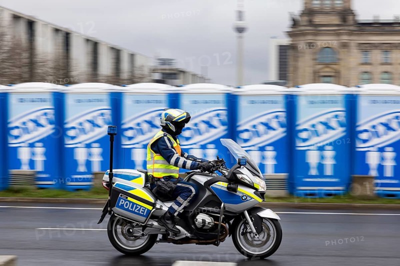 Reichstag Berlin with waving flags. Before that, mobile toilets for a major event. Police motorcycle. Contributor. smudge effect. Berlin, Germany