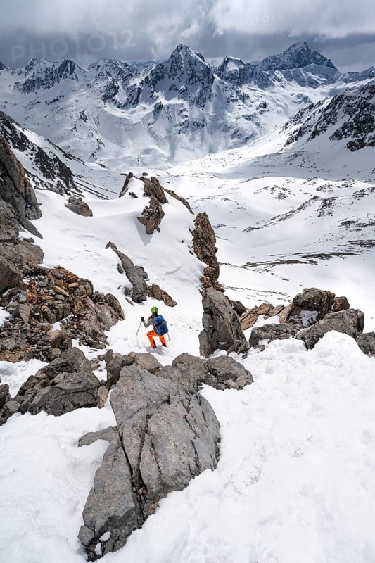 Mountaineer descending Piz Laviner, view of mountain panorama in wintry mountain landscape with dramatic clouds, Grisons Haute Route, Albula Alps, Rhaetian Alps, Grisons, Eastern Switzerland, Switzerland