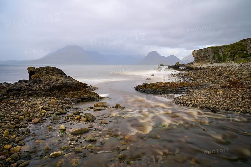River flows into the sea along a rocky coast under grey skies, Elgol Beach, Elgol, Isle of Skye, Scotland, United Kingdom, Great Britain